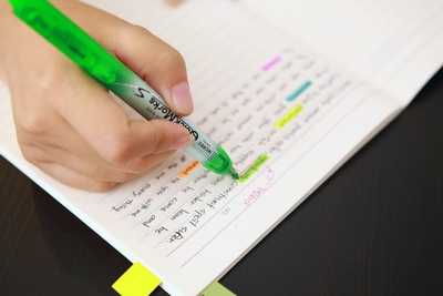 image of an individual's hand highlighting text on notebook paper